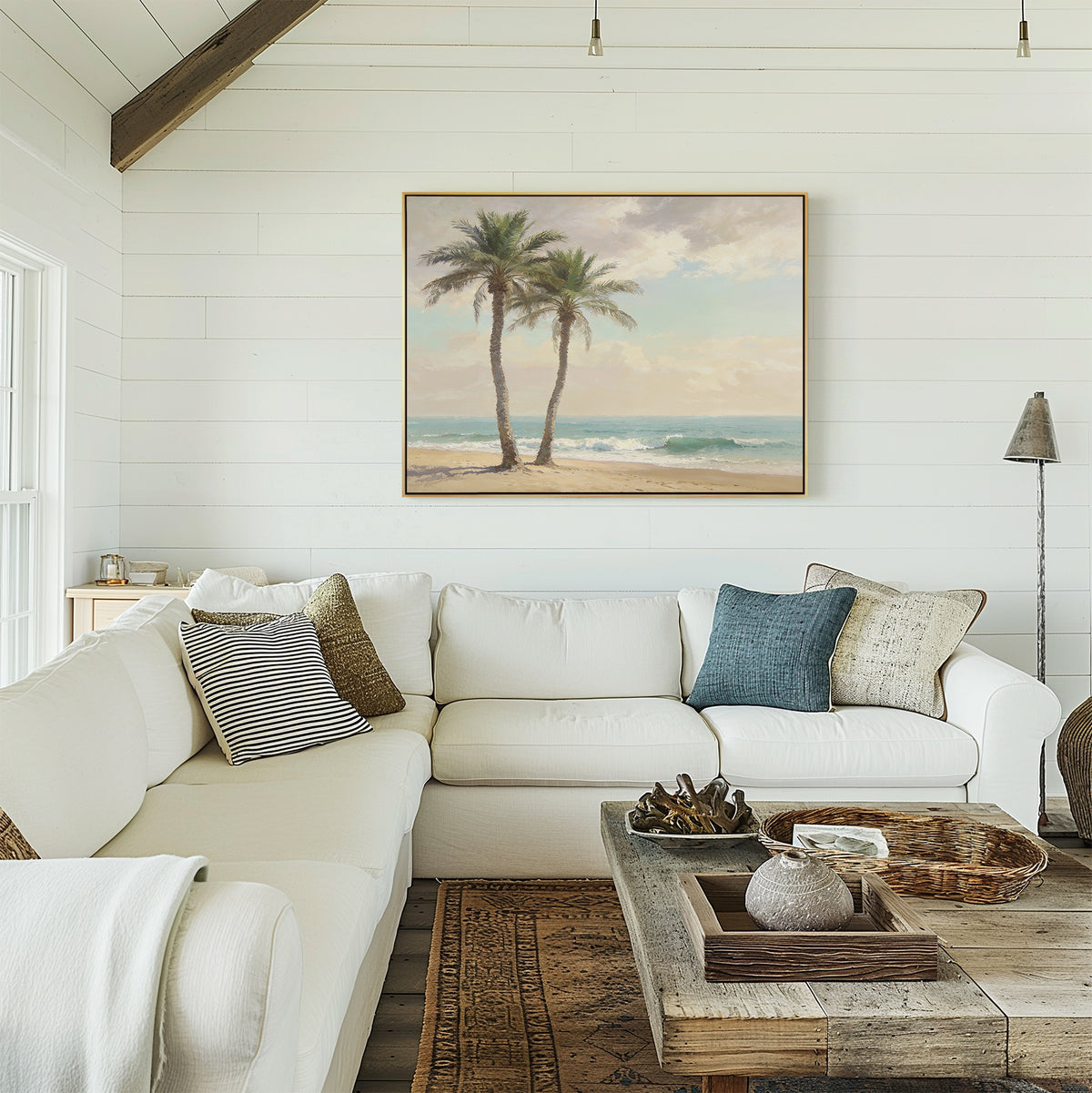 A bright, airy living room with a white sectional sofa, patterned pillows, a rustic wooden coffee table, and serene Paradise Found Canvas Art - Horizontal featuring palm trees hangs on a shiplap wall as natural light streams in from the window.