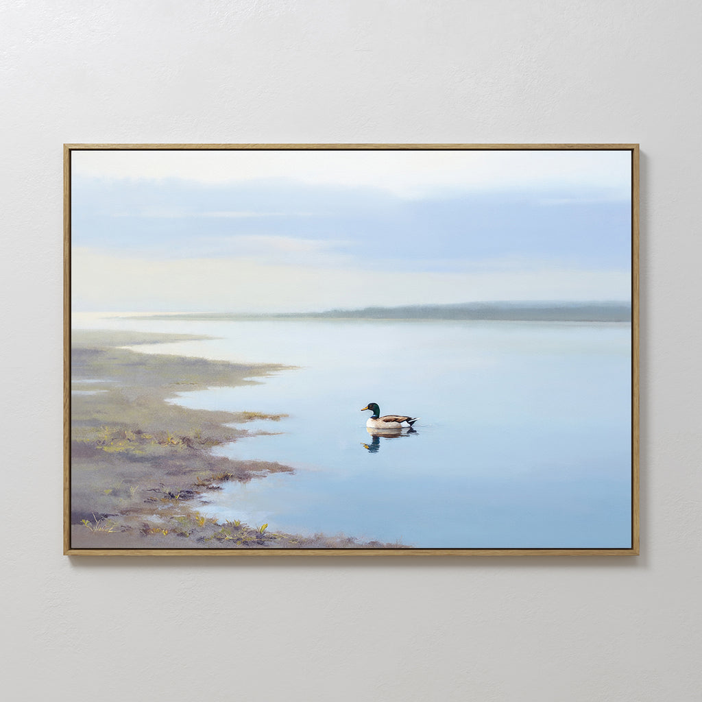 The "Peaceful Duck Haven Canvas Art - Horizontal" is a framed painting of a calm lakeside, with a duck gliding near the shore, its reflection visible in the still blue water beneath a cloudy sky.