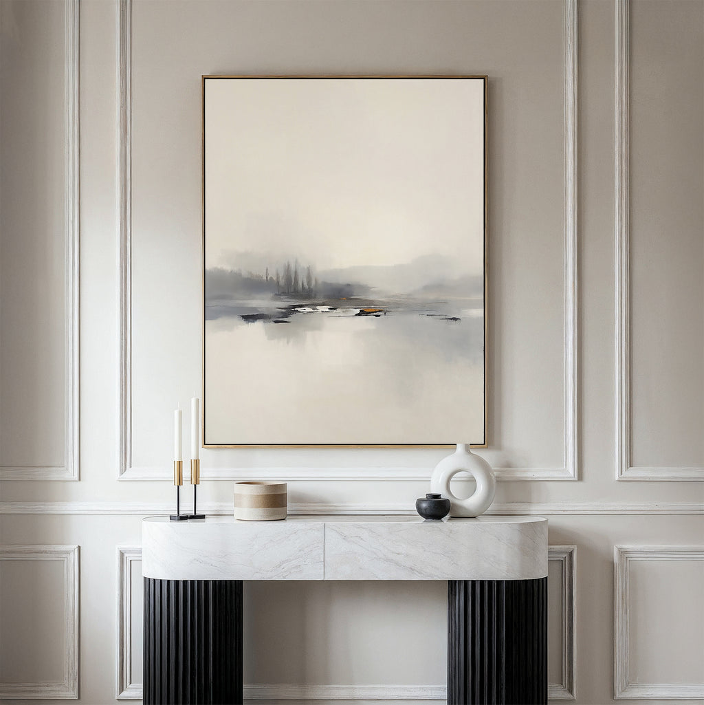 A minimalist room features the Peaceful Lake Morning Canvas Art - Vertical above a modern console table, decorated with candles, a white sculpture, and a small wooden container for a peaceful atmosphere.