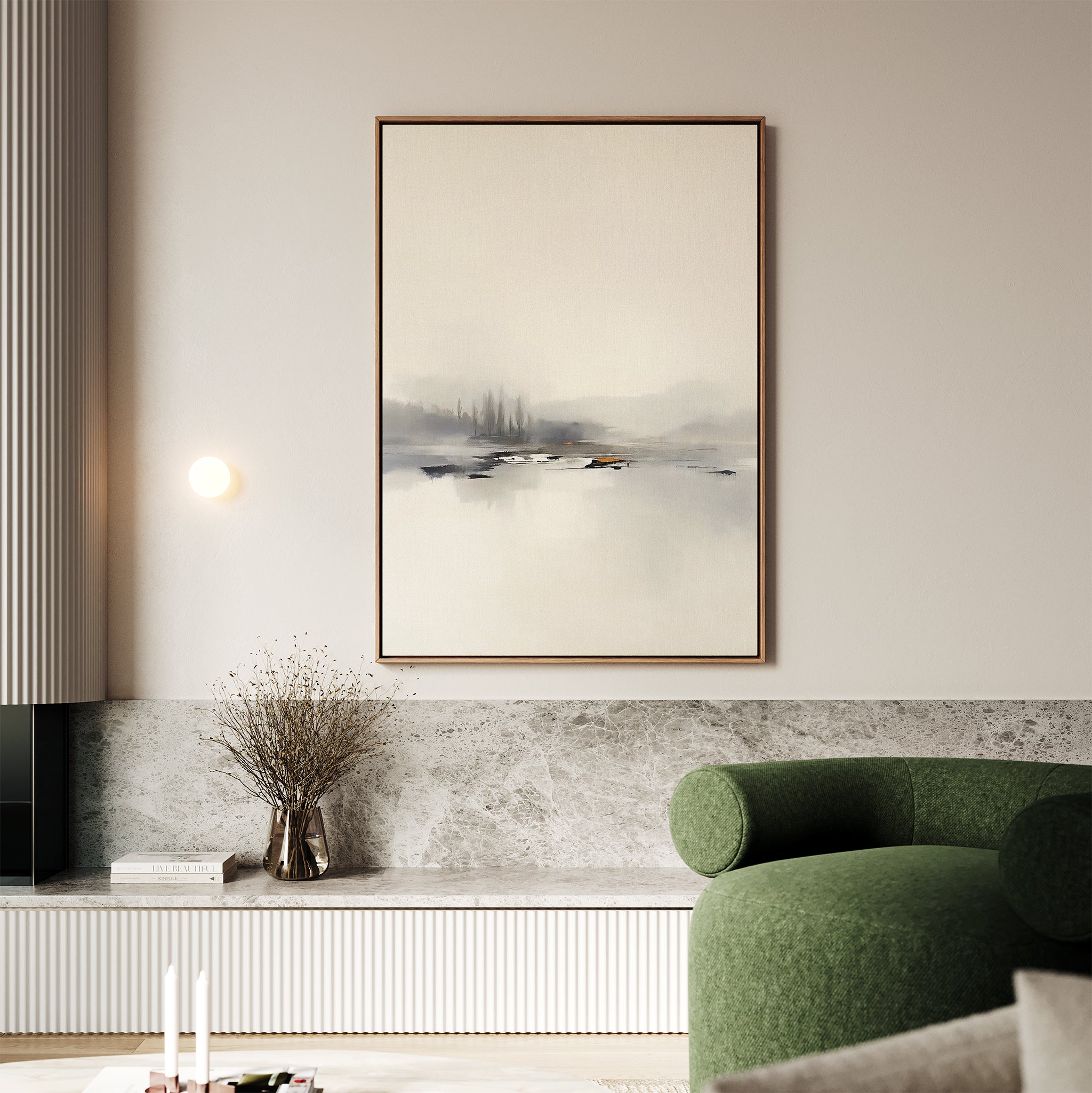 A modern living room features the Peaceful Lake Morning Canvas Art - Vertical, a green curved sofa, a marble accent wall, and dried flowers on a low shelf, creating a tranquil atmosphere.