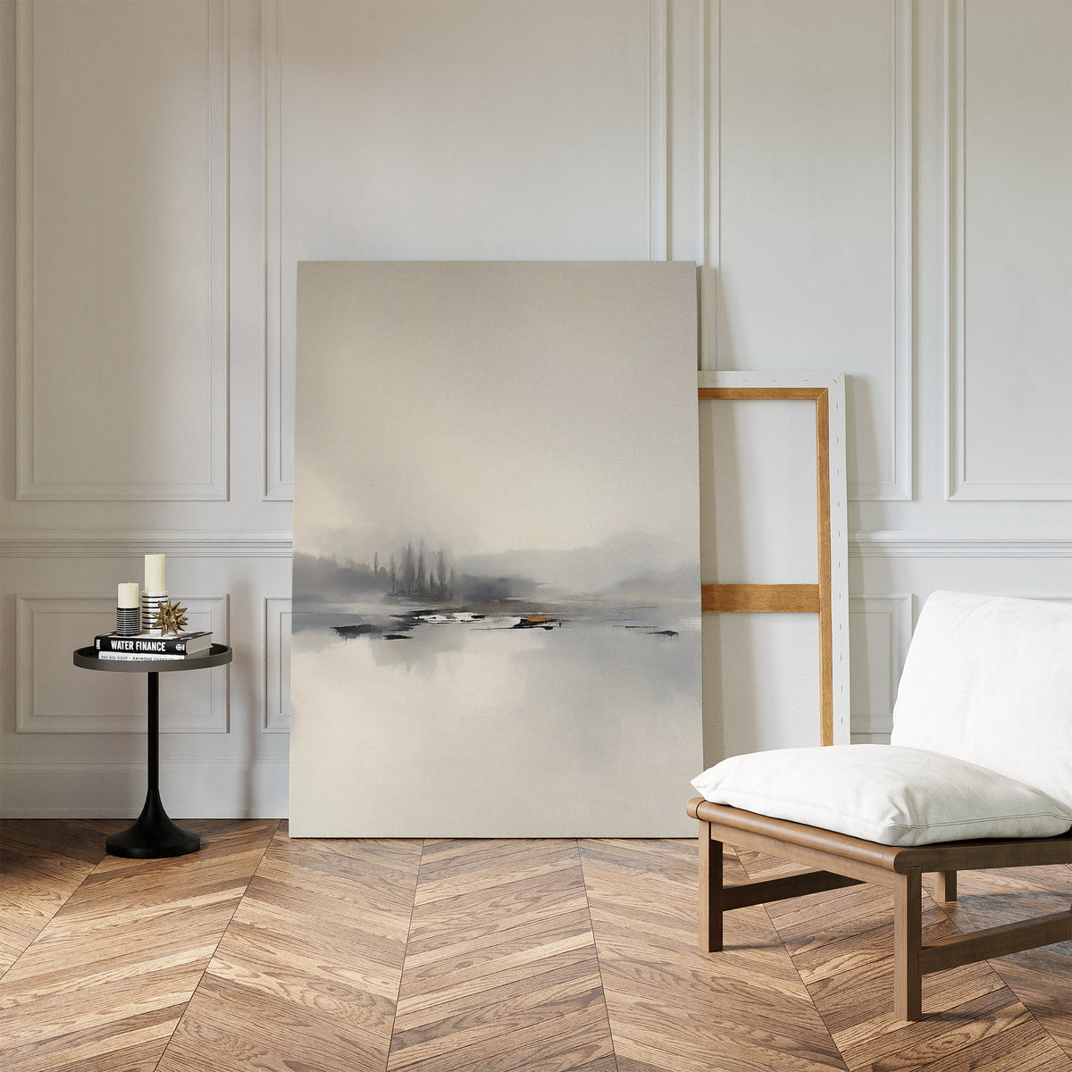 A serene, minimalist room with a white cushioned chair, a small round black table with books and candles, and the Peaceful Lake Morning Canvas Art - Vertical resting against a paneled white wall on herringbone wood floors.