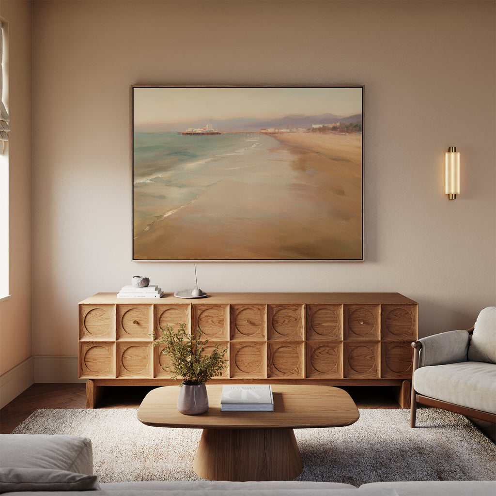 A modern living room features a light gray sofa, wooden coffee table, textured wood sideboard, neutral rug, and the Pier Dreams Canvas Art - Horizontal above the sideboard. A wall sconce and window offer soft lighting.