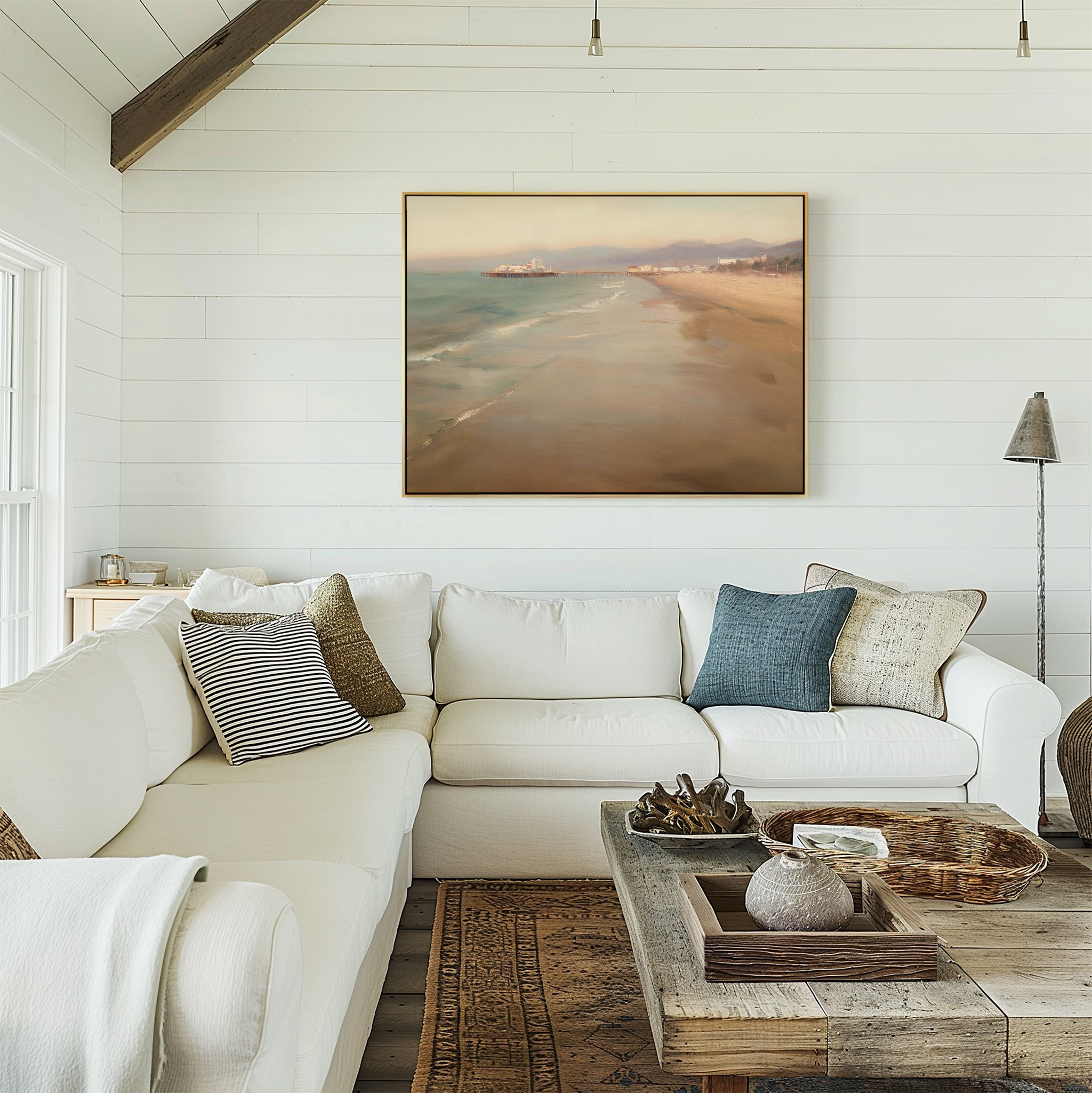 A cozy living room features a white sectional, assorted throw pillows, a wooden coffee table with decor, and the Pier Dreams Canvas Art - Horizontal gracing the white shiplap wall.