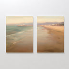 Pier Dreams - Set of 2 features two side-by-side canvases of a serene beach sunset, calm waves, and a pier with buildings beneath a pastel sky—ideal coastal wall art for creating relaxing spaces.