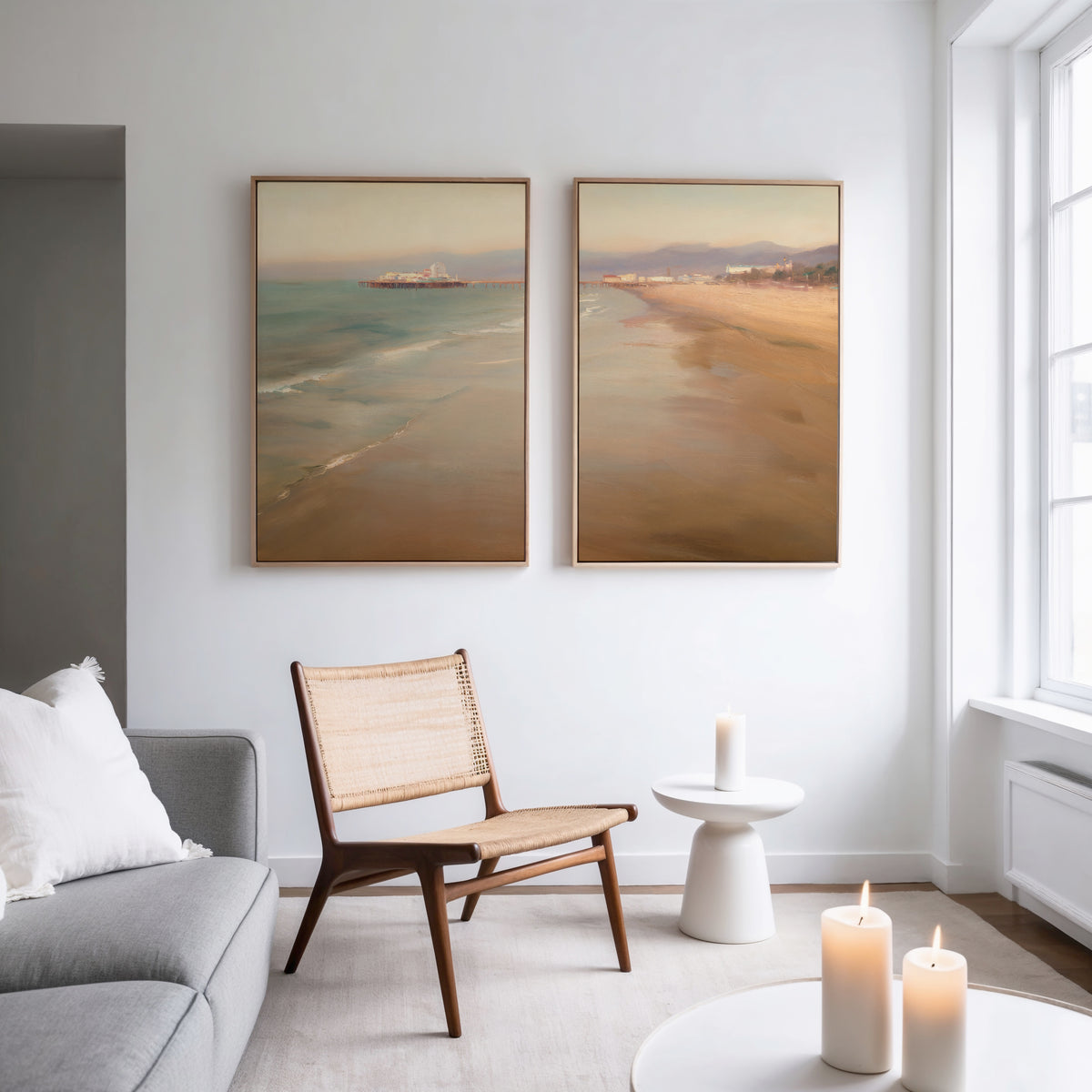 A modern living room featuring a woven chair, a round side table with candles, a sofa with a white pillow, and Pier Dreams - Set of 2 large coastal canvas prints on a white wall. Three candles glow softly on the table and windowsill.
