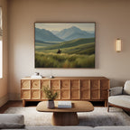 A cozy living room with light walls, a beige sofa, and a wooden coffee table. Above the sideboard hangs the Prairie Wanderer Canvas Art - Horizontal, featuring a rider on horseback and adding western charm to the space.