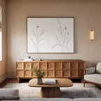 A modern living room features a light wood sideboard, beige sofa, low wooden coffee table, and a vase with flowers. Above the sideboard hangs "Prairie Whispers Canvas Art - Horizontal," adding botanical charm to the tranquil, neutral-toned space.