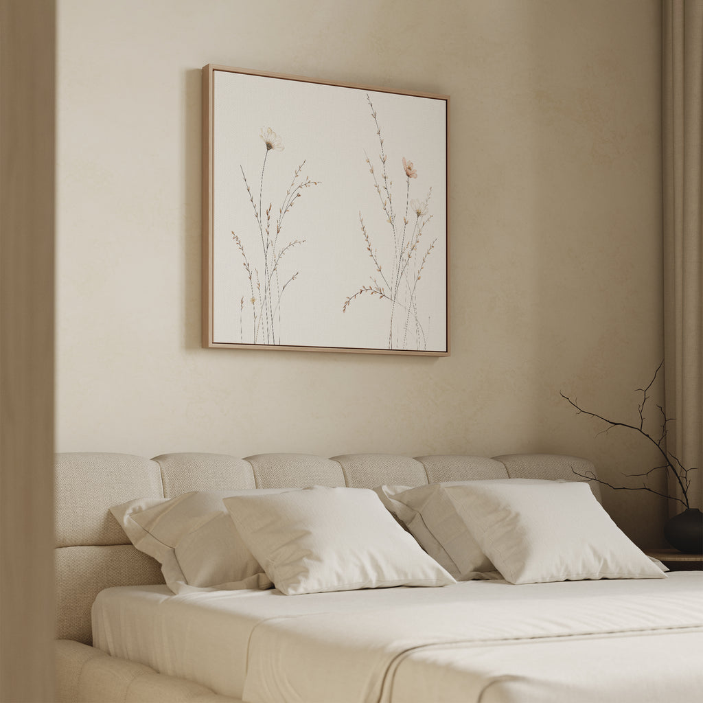 A minimalistic beige bedroom features a low bed with cream bedding and the Prairie Whispers Canvas Art - Square, showcasing delicate botanical flowers, hanging above the headboard.