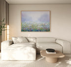 A modern living room features a large cream sectional sofa, a light wood coffee table with a black bowl, and the Purple Haze Canvas Art - Horizontal framed above the sofa. Neutral tones and natural light complete the elegant decor.