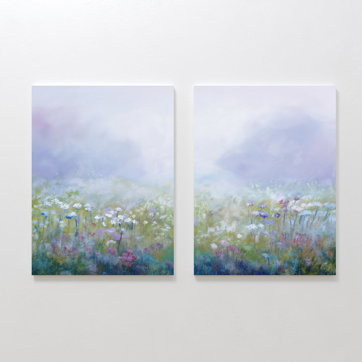 Purple Haze - Set of 2 features dreamy canvas paintings with pastel wildflowers and misty backgrounds in purples, blues, greens, and whites—perfect as living room or bedroom decor on a light wall.