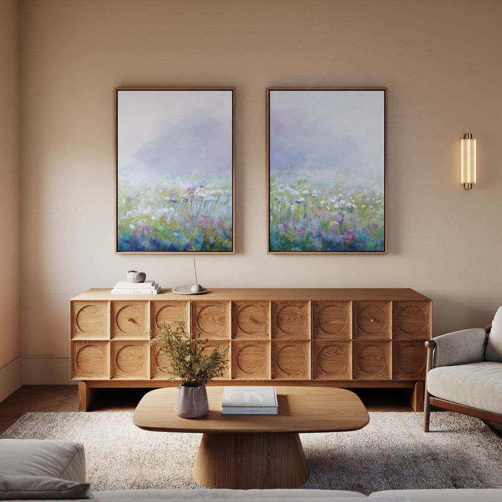 A cozy living room features a wooden sideboard with the "Purple Haze - Set of 2" abstract floral canvases above, a round coffee table displaying a flower vase, neutral-toned armchairs, and a modern wall sconce for chic decor.