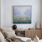 A cozy living room features a beige sofa, neutral cushions, wooden sideboard, decorative vases, books, and the Purple Haze Canvas Art - Square as a stunning focal point for inviting decor.