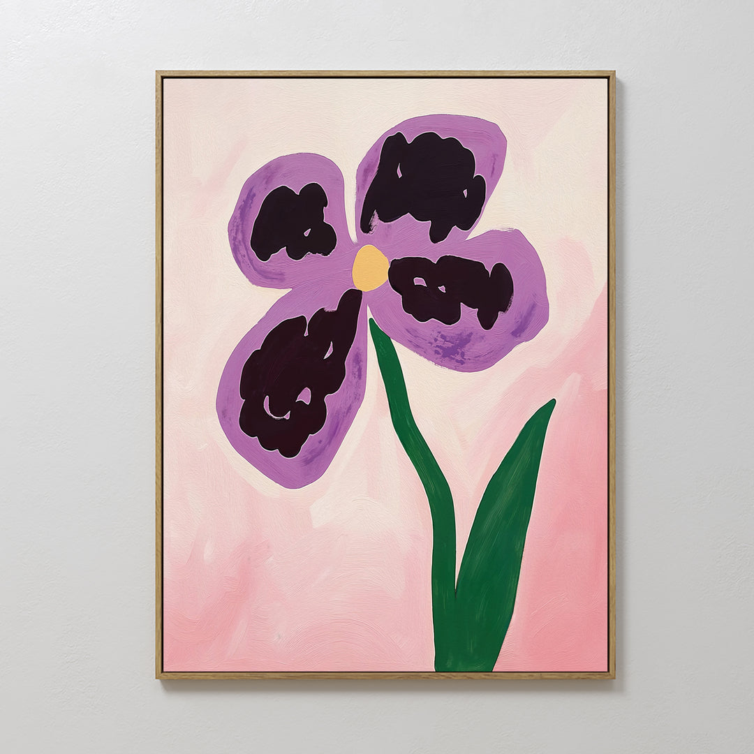 Purple Pansy Canvas Art - Vertical features a botanical print of a purple pansy with four petals, a yellow center, and green stem on a pink background. The artwork is framed in thin gold and displayed on a white wall.