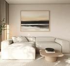 Minimalist living room featuring a light beige sectional sofa, wooden coffee table with black bowl, Quiet Shoreline Canvas Art - Horizontal on the wall, and a floor plant by the window. The décor is neutral and modern.