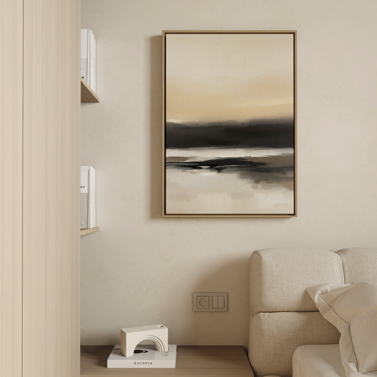 A minimalist living room with a beige couch, the Quiet Shoreline Canvas Art - Vertical in neutral tones on the wall, a wooden shelf with white books, and a small decorative object on the floor.