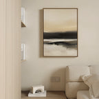A minimalist living room with a beige couch, the Quiet Shoreline Canvas Art - Vertical in neutral tones on the wall, a wooden shelf with white books, and a small decorative object on the floor.