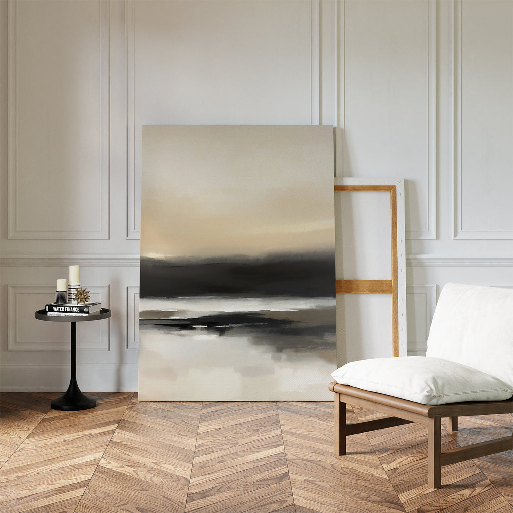 A minimalist room with herringbone wood flooring features the Quiet Shoreline Canvas Art - Vertical leaning against a paneled white wall, next to a cushioned chair and a small round table with candles and books.