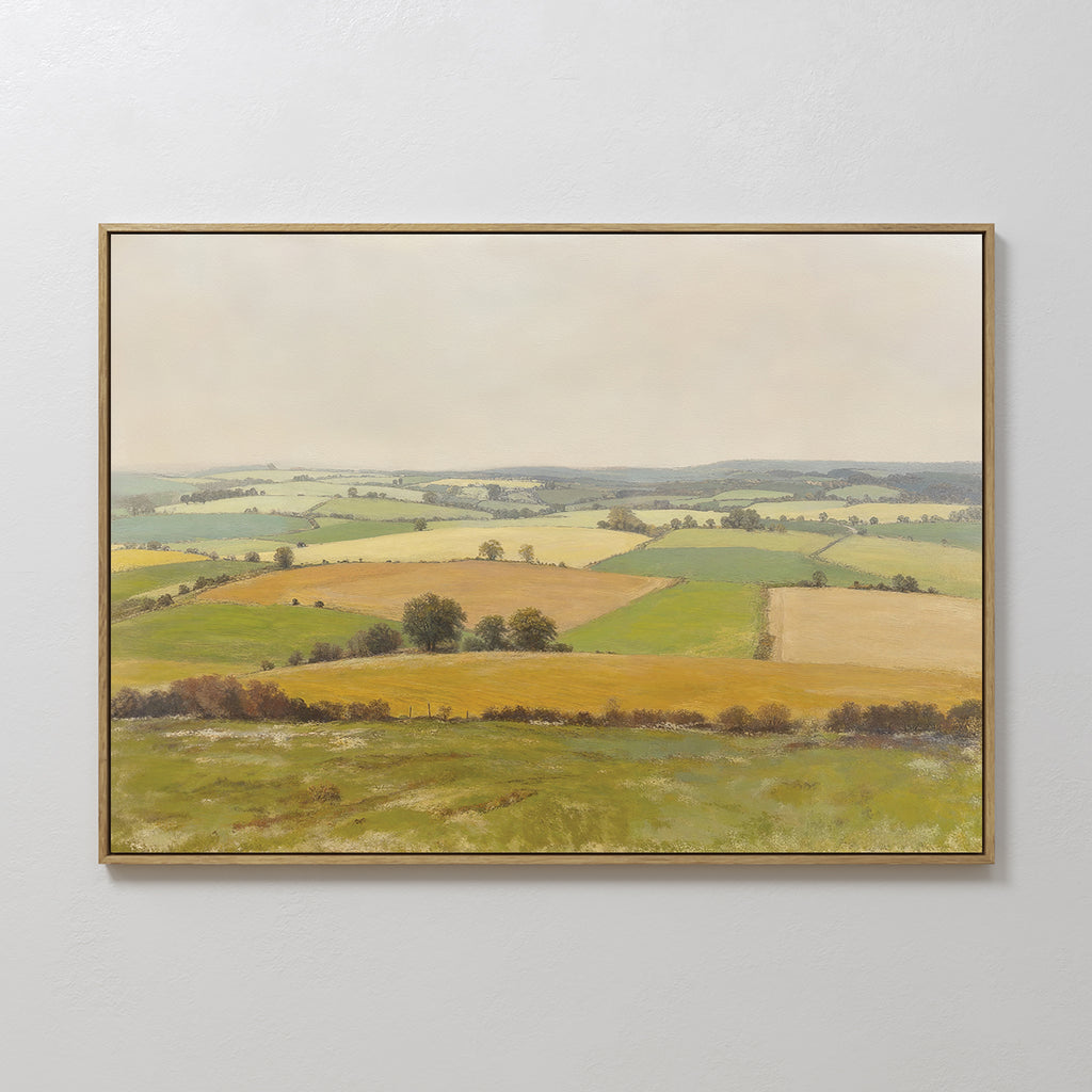 The Rolling Fields Canvas Art - Horizontal features a pastoral countryside landscape of rolling hills, green and yellow fields, scattered trees, and a cloudy sky, displayed on a plain white wall.