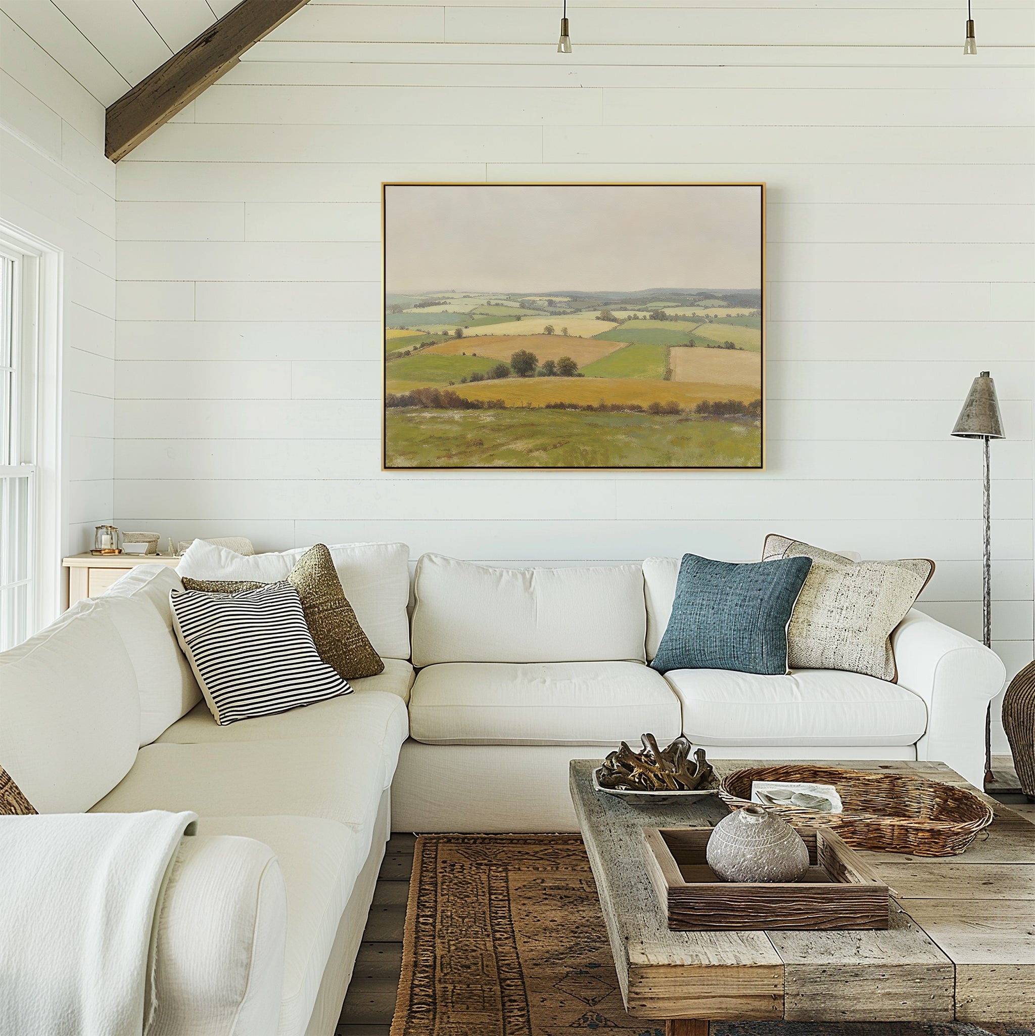 A bright, cozy living room with a white sectional sofa, assorted throw pillows, rustic wooden coffee table, and the Rolling Fields Canvas Art - Horizontal displayed on the white shiplap wall.