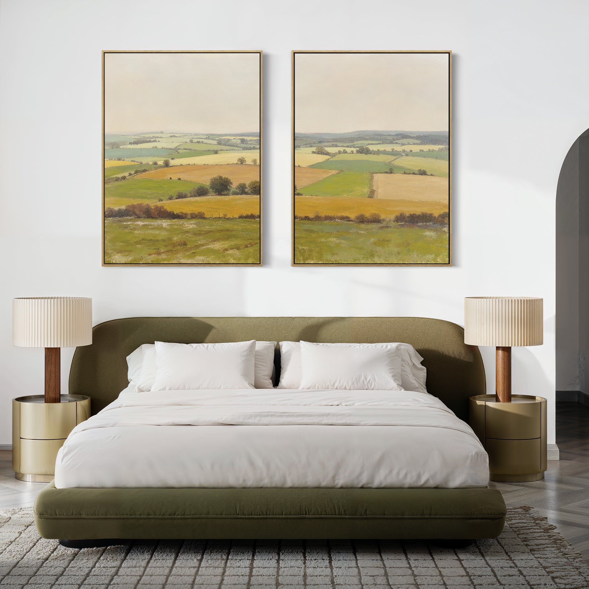 A modern bedroom features a green upholstered bed, white bedding, beige nightstands with matching lamps, and "Rolling Fields - Set of 2" wall art above the bed, showcasing tranquil pastoral countryside scenes in elegant frames.