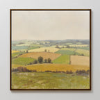 Rolling Fields Canvas Art - Square: This framed canvas print features serene rolling hills and patchwork fields in green and yellow beneath a pale, cloudy sky, with hedgerows and scattered trees completing the tranquil landscape.