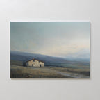 Rustic Solitude Canvas Art - Horizontal features a solitary farmhouse set amid gentle, grassy hills beneath a cloudy sky. Muted colors and an open landscape evoke calm and serenity, making it ideal decor for tranquil spaces.
