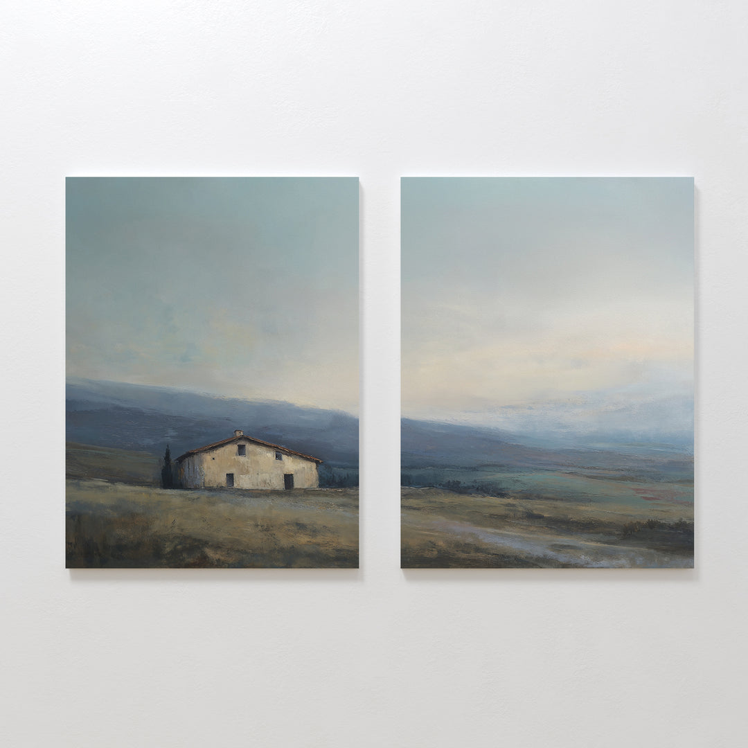 The "Rustic Solitude - Set of 2" features side-by-side paintings of a tranquil farmhouse on grassy plains with soft clouds, blending muted blues, greens, and earth tones—ideal rustic wall art for peaceful countryside decor.