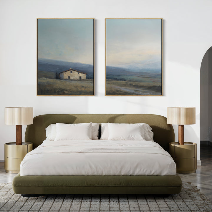 A modern bedroom with a low olive-green bed, neutral bedding, two gold side tables with beige lamps, and "Rustic Solitude - Set of 2" landscape paintings above the bed for a minimalist and calming vibe.