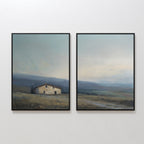 The Rustic Solitude - Set of 2 features framed wall art, each depicting an old house, grassy fields, distant hills, and a soft cloudy sky in muted earthy tones for a charming farmhouse look.