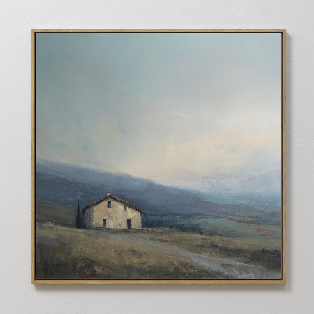 The Rustic Solitude Canvas Art - Square features a small house on a grassy hillside beneath a cloudy sky with distant blue-gray mountains, creating tranquil landscape decor for any space.