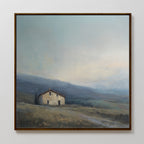 The Rustic Solitude Canvas Art - Square features a small, rustic house on a grassy hill beneath a cloudy sky and blue-gray mountains—ideal landscape decor or farmhouse wall art for creating a calm, inviting space.