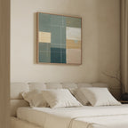A modern bedroom with a beige bed and four white pillows features minimalist decor. Above the bed hangs the Sage Compartments Canvas Art - Square, showcasing geometric shapes in teal, yellow, white, and beige. A bare branch sits in a nearby vase.