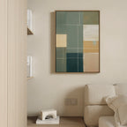 A minimalist living room corner featuring a beige sofa, a small shelf with books and decor, and the Sage Compartments Canvas Art - Vertical as modern wall art in muted green, tan, and cream tones.