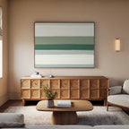 A cozy living room features a light sofa, wooden coffee table, and textured wooden sideboard. Above the sideboard hangs the Sage Gradient Canvas Art - Horizontal, showcasing abstract green and white stripes. A soft rug covers the floor.