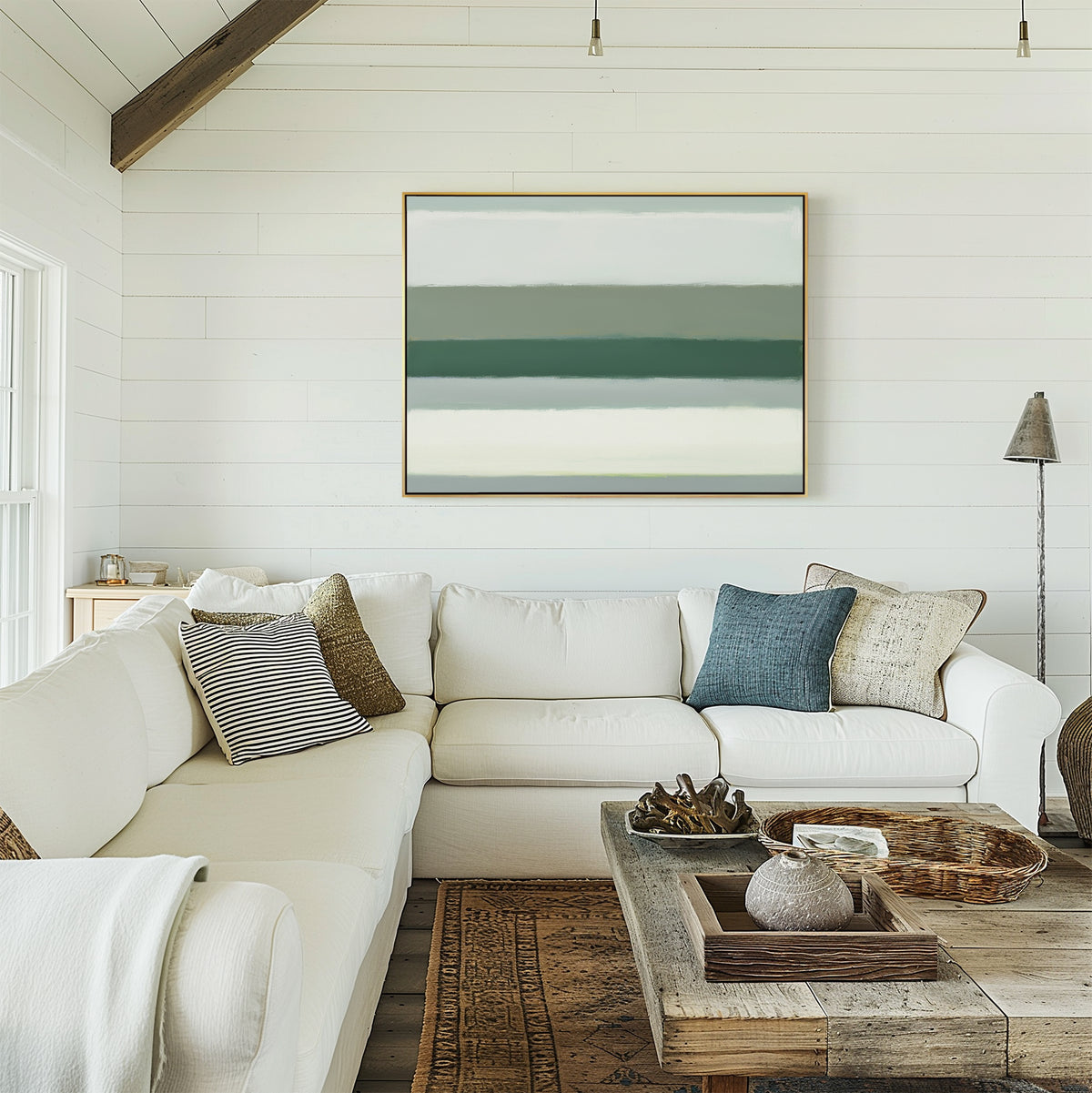 A bright living room with white shiplap walls, a large white sectional with assorted pillows, a rustic wood coffee table with decor, and the Sage Gradient Canvas Art - Horizontal displayed on the wall.