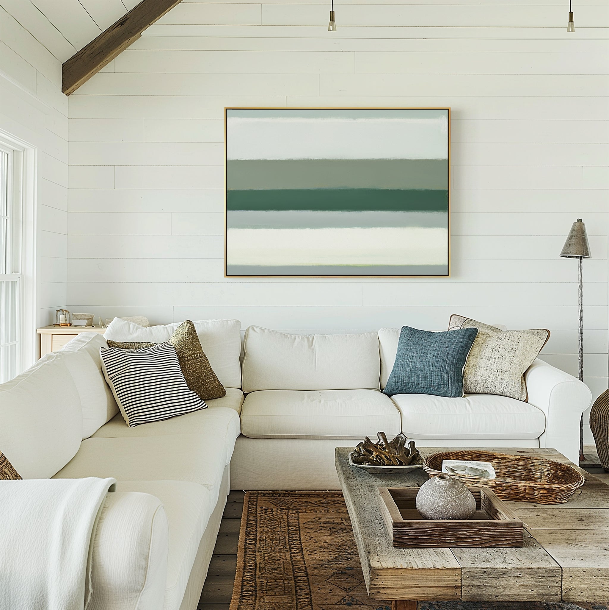 A bright living room with white shiplap walls, a large white sectional with assorted pillows, a rustic wood coffee table with decor, and the Sage Gradient Canvas Art - Horizontal displayed on the wall.