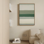A modern, minimal living space with a beige sofa, light wooden shelves for books, and Sage Gradient Canvas Art - Vertical—a calming abstract piece with green and white stripes—displayed on a cream wall.