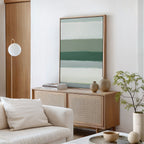 A minimal living room features a light wood cabinet, ceramic vases, books, a potted plant, white sofa with cushions, round hanging lamp, and the Sage Gradient Canvas Art - Vertical for a serene vibe in neutral and green tones.