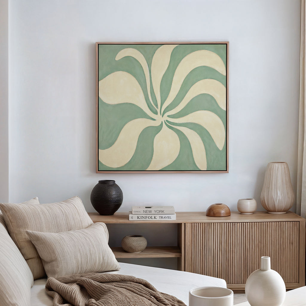 A modern, minimal living room featuring a beige sofa with neutral cushions, a wooden sideboard with vases and books, and the Sage Meditation Canvas Art - Square showcasing abstract green and cream artwork on the wall.