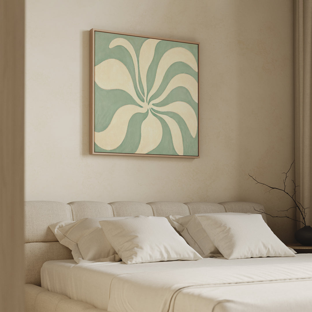 A modern bedroom with a beige upholstered bed, white bedding, four pillows, and the Sage Meditation Canvas Art - Square in sage green above the headboard. A bare branch decorates the nightstand beside floor-length curtains.