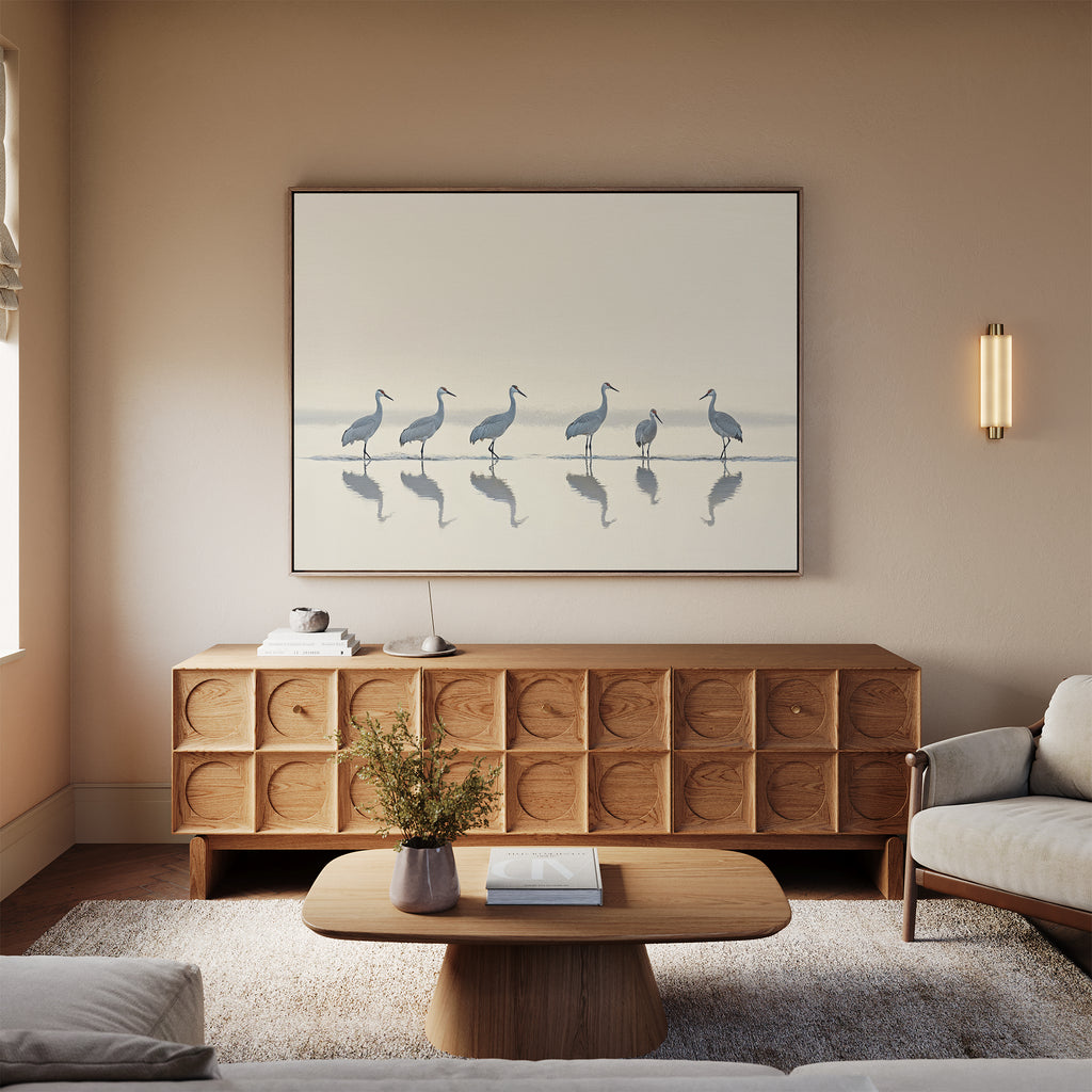 A minimalist living room with a light sofa, wooden coffee table, carved sideboard, vase of flowers, and the "Sandhill Procession Canvas Art - Horizontal" adds serene elegance. Neutral tones and soft lighting evoke a calm Nordic Park ambiance.