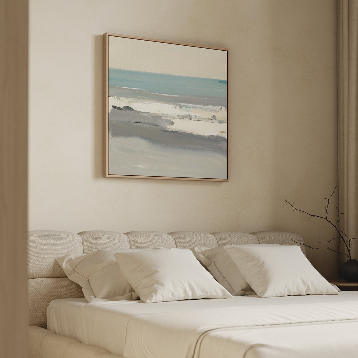 A minimalist bedroom features a beige upholstered bed with white bedding and soft neutrals. Above the bed, the Sandy Retreat Canvas Art - Square in blue, beige, and gray evokes seaside vibes. A bare branch decorates the nightstand.