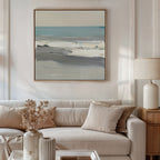 A neutral-toned living room features a beige sofa with matching pillows and a dried floral arrangement. Above, the Sandy Retreat Canvas Art - Square adds gentle seaside vibes with its serene blue and gray coastal scene.
