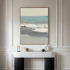 The Sandy Retreat Canvas Art - Vertical hangs on a white paneled wall above a white marble console table with black legs, styled with minimalist objects and candles for subtle seaside vibes.