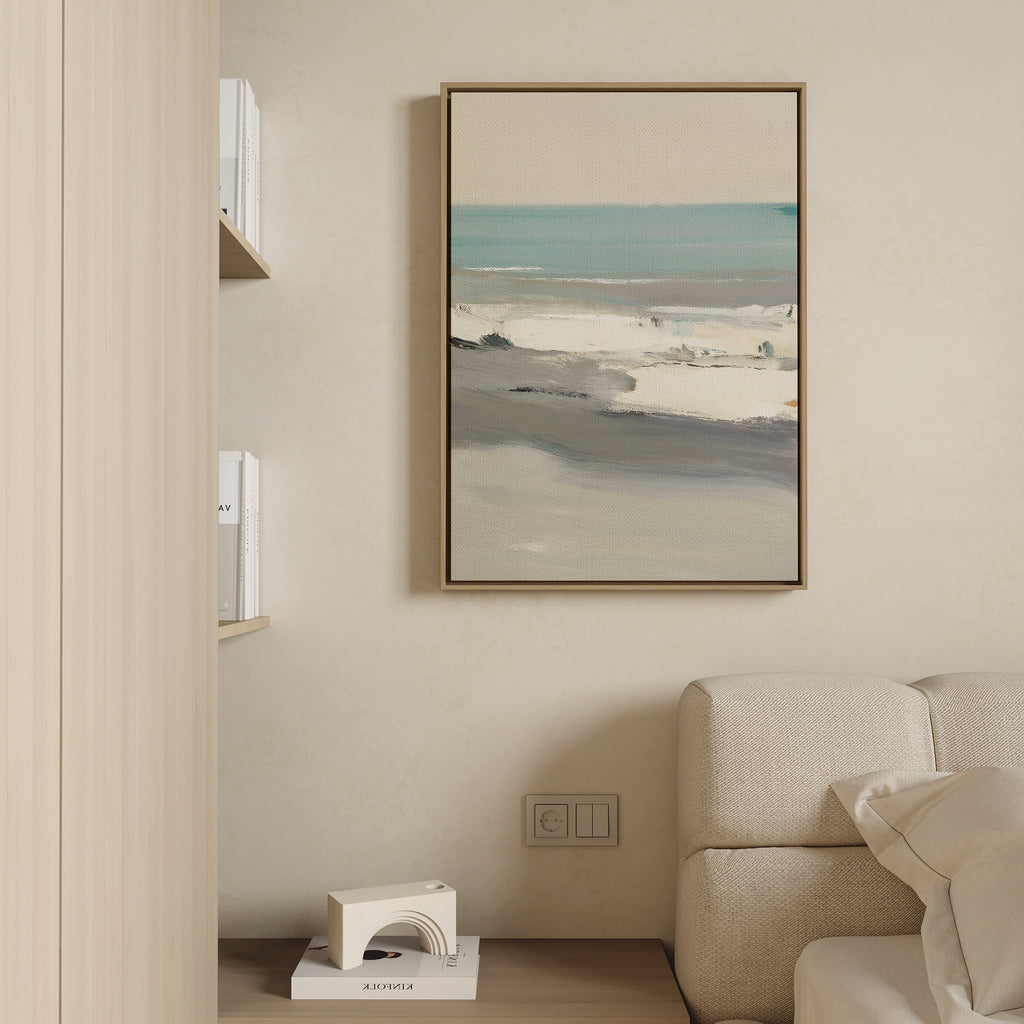 A modern living room features a beige sofa and light wooden shelves with books, while the Sandy Retreat Canvas Art - Vertical hangs above an outlet and bookend, bringing subtle seaside vibes to the cream-colored wall.