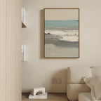A modern living room features a beige sofa and light wooden shelves with books, while the Sandy Retreat Canvas Art - Vertical hangs above an outlet and bookend, bringing subtle seaside vibes to the cream-colored wall.