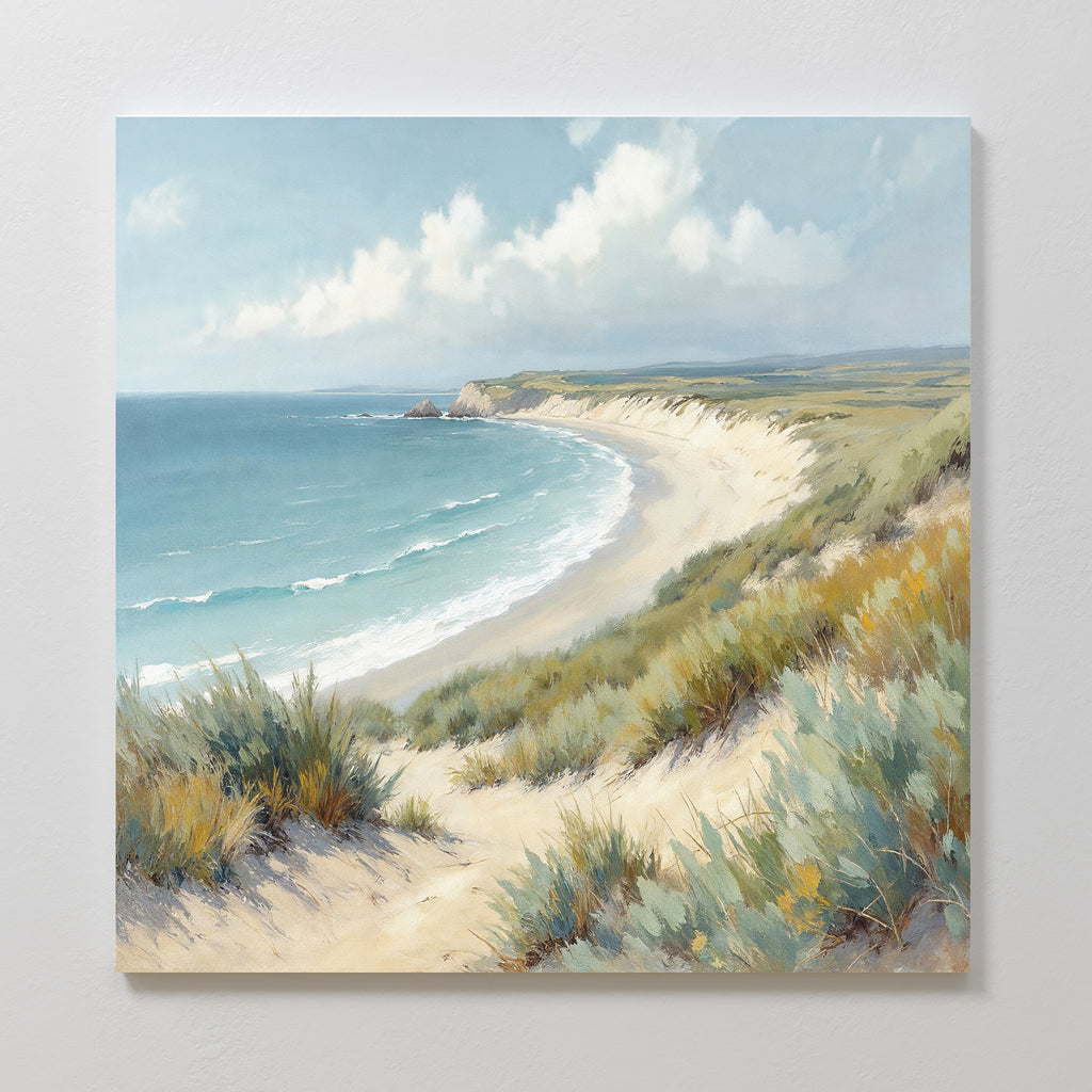 Sandy Shores Canvas Art - Square captures a sandy beach with gentle waves, grassy dunes, and a partly cloudy sky. The coastal landscape curves into the distance with green hills—ideal for adding serene beach vibes to your wall.