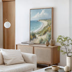 A coastal-themed living room features a light wood cabinet, beige vases, and the Sandy Shores Canvas Art - Vertical. A white sofa with a cushion and a modern globe lamp enhance the calm, airy vibe inspired by serene seaside escapes.