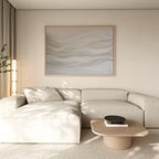A modern living room with a light beige sectional sofa, neutral cushions, a light wooden coffee table with a black bowl, Sandy Hues Abstract Canvas Art on beige walls, and natural light streaming through sheer curtains.
