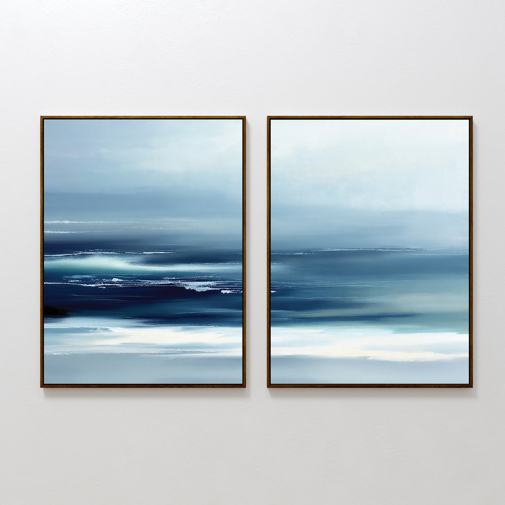 The Sapphire Current - Set Of 2 showcases abstract prints in blue and white with blurred horizontal lines, evoking a serene seascape. Each tranquil piece is framed in a slim dark frame and displayed side by side on a white wall.